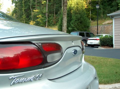1998 Ford Taurus - Rear view of a silver 1998 Ford Taurus SE, with other vehicles parked nearby.