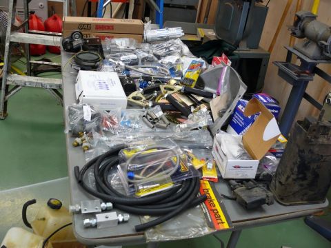 1976 Chevrolet Corvette - A collection of automotive parts is spread across a table in a workshop setting.