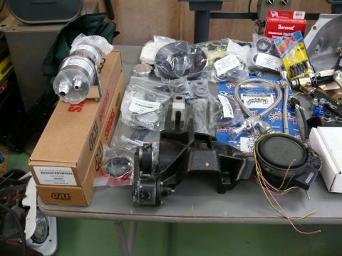 1976 Chevrolet Corvette - A collection of automotive parts, including a chrome oil filter and engine mount, are laid out on a table.