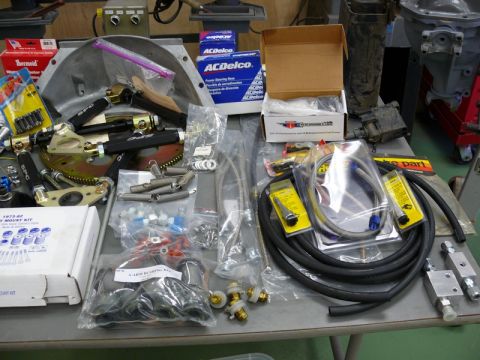 1976 Chevrolet Corvette - Various automotive parts laid out on a table, including engine components and hardware.