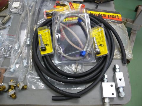 1976 Chevrolet Corvette - A collection of new and packaged automotive brake and fuel line components are displayed on a workbench.