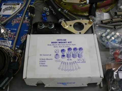 1976 Chevrolet Corvette - Various car parts and hardware are laid out, including a body mount kit for 1973-82 vehicles.