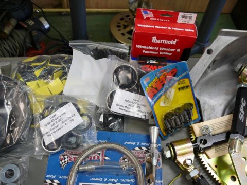 1976 Chevrolet Corvette - A collection of automotive parts, including brake caliper rebuild kits and vacuum tubing, are laid out on a surface.