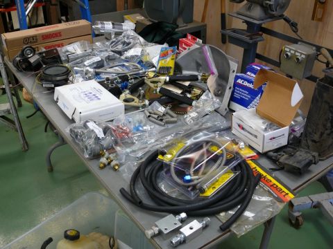 1976 Chevrolet Corvette - A collection of automotive parts and tools are spread across a table in a workshop setting.