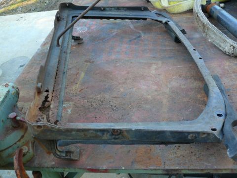 1976 Chevrolet Corvette - This is a rusted metal frame part, possibly from a car, resting on a workbench.