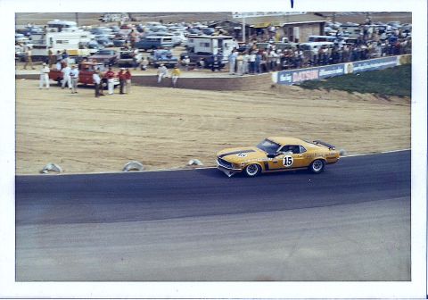 1973 Ford Mustang - A yellow 1970 Ford Mustang Boss 302 race car numbered 15 navigates a turn on a race track.