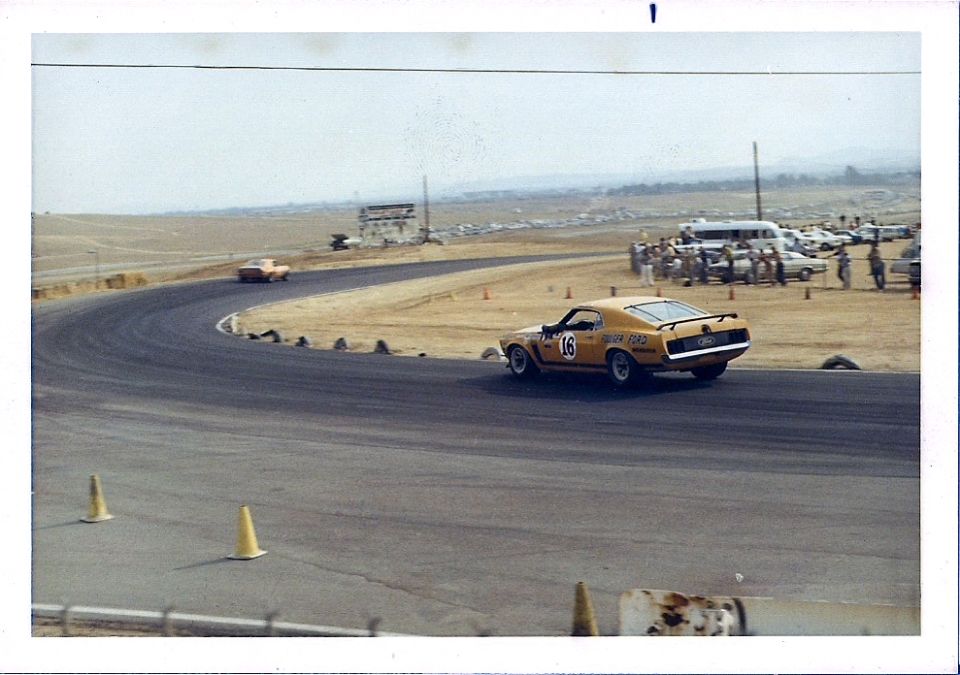 Yellow 1970 race car with number 16 on a track, rear view