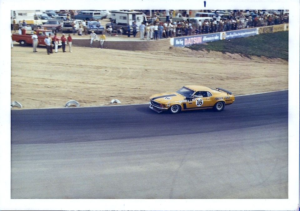 yellow race car with black stripes and number 16 on door, on a track