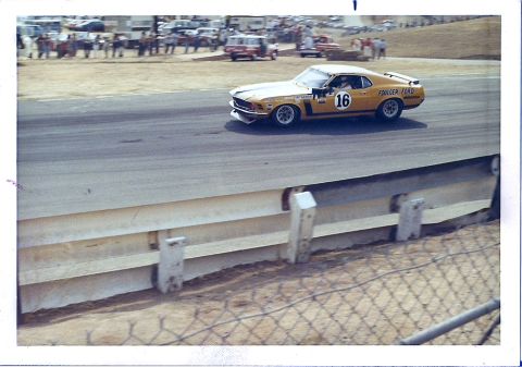 1973 Ford Mustang - A yellow race car with the number 16 and "FOLLMER FORD" branding speeds around a track.