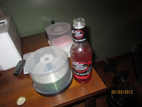 1979 Ford Bronco - A bottle of Mike's Hard Cranberry Lemonade sits on a table with a CD spindle, remote controls, and dumbbells.