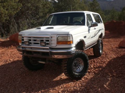 1996 Ford Bronco - White 1996 Ford Bronco lifted with large off-road tires, parked on gravel.