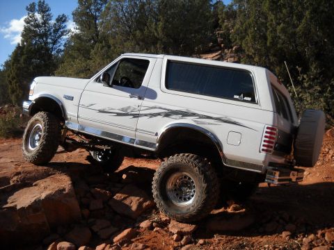 1996 Ford Bronco - 1996 Ford Bronco navigating a rocky trail with its tires on large boulders.