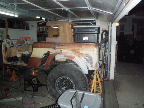 1961 International Scout 800 - Vehicle body in a garage, appears to be undergoing restoration or modification with parts removed.