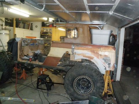 1961 International Scout 800 - Vehicle body in a state of disrepair, with large tires and frame visible in a workshop setting.