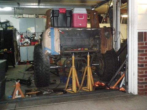 1961 International Scout 800 - This heavily modified off-road vehicle is in a garage, supported by jack stands for maintenance.