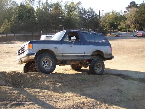 1989 Ford Bronco - This lifted Ford Bronco navigates an off-road course with its front wheels on an incline.