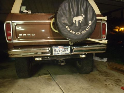 1979 Ford Bronco - The rear of a brown 1979 Ford Bronco is visible, a spare tire carrier and a Texas license plate.