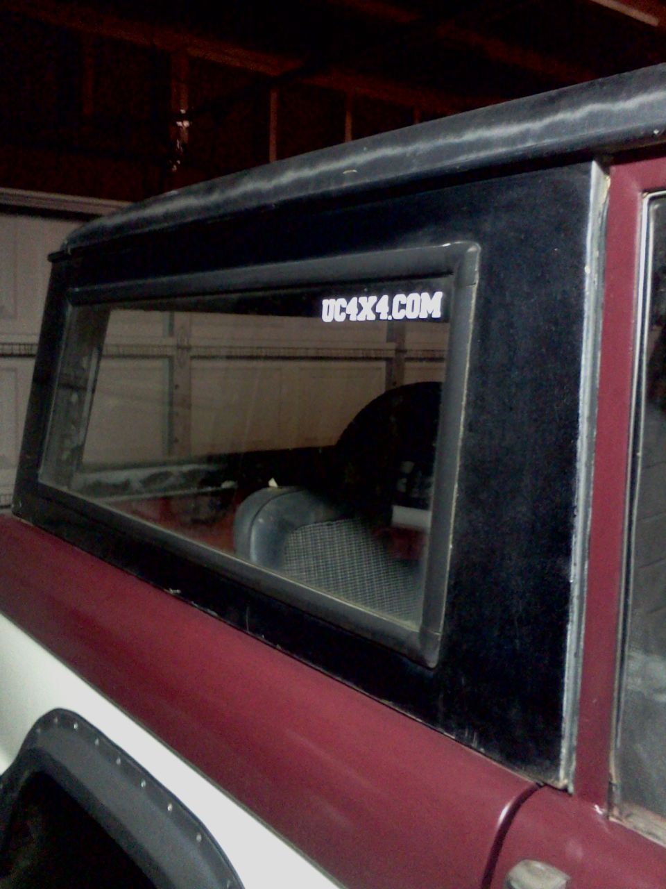Maroon and white 1968 Ford Bronco side view with UC4X4.COM sticker on rear window