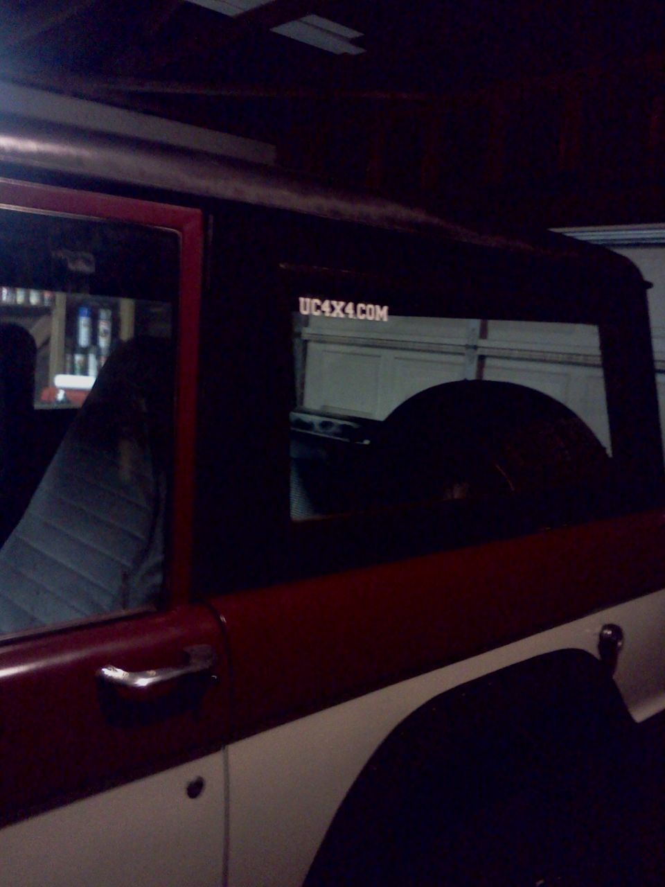 Side view of a red and white SUV with a UC4X4.COM sticker on the rear window