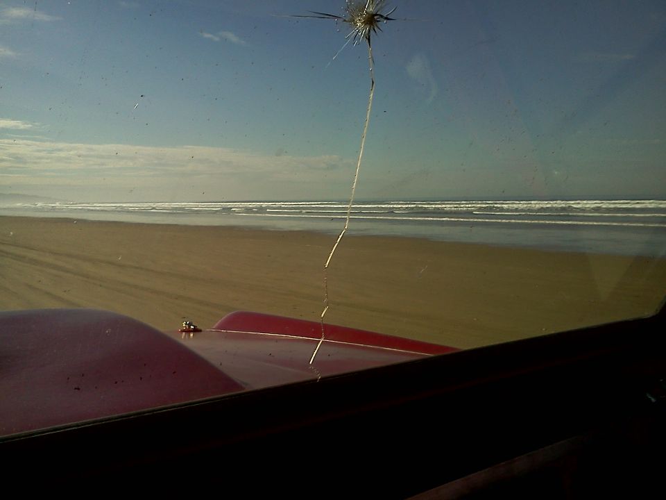 Red vehicle hood with a large crack on the windshield, viewed from inside