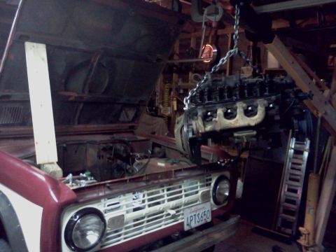 1968 Ford Bronco - The engine is being removed from a 1968 Ford Bronco in a workshop setting.