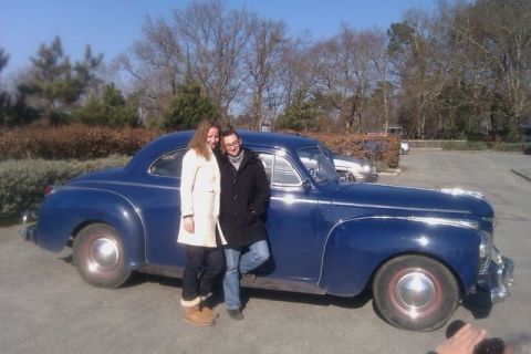 1991 Ford Crown Victoria - A blue coupe from the 1940s is parked outside with two individuals posing beside it.