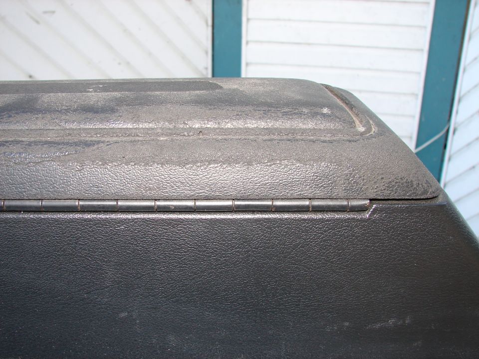 Black textured truck bed cover hinge with visible wear and dust