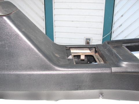 1973 Ford Ranchero - Close-up of a vehicle's interior center console, showing a black textured plastic finish and an open compartment.