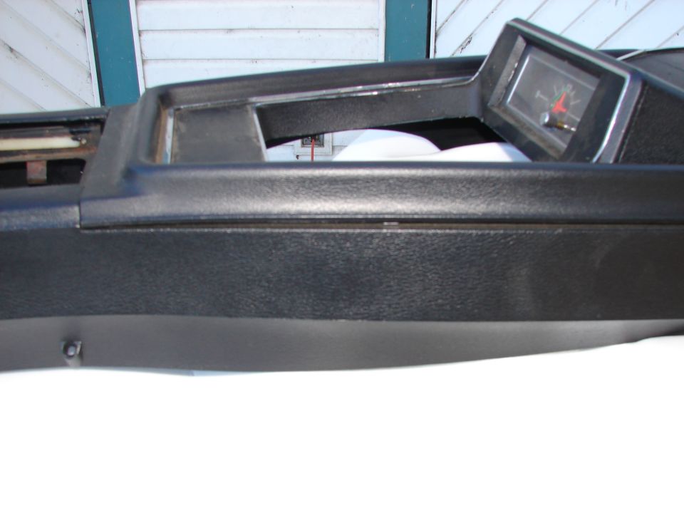Dashboard trim piece with a clock inset. The clock has red and black hands