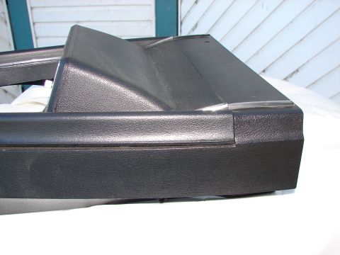 1973 Ford Ranchero - A close-up view of a textured black plastic automotive interior trim piece with a thin chrome accent.