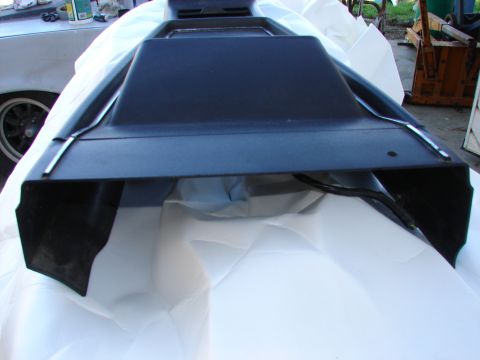 1973 Ford Ranchero - A black plastic car part with chrome trim is shown from a low angle, resting on a white surface.