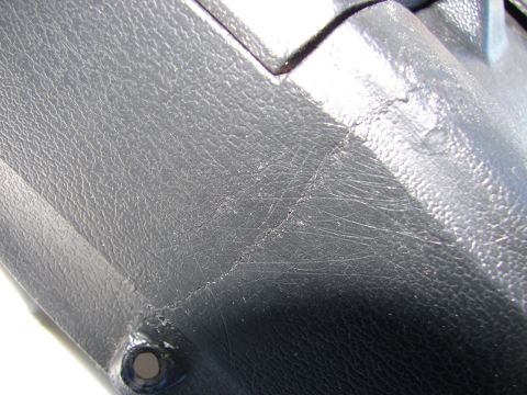 1973 Ford Ranchero - Close-up of a worn black interior trim piece, showing scratches and a crack.
