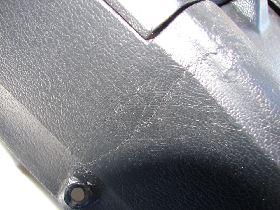 Black textured plastic interior trim with visible scratches and a small crack