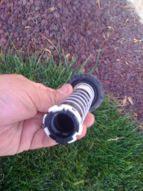 1968 Ford Mustang - A hand holds a disassembled sprinkler head, revealing its internal spring mechanism.