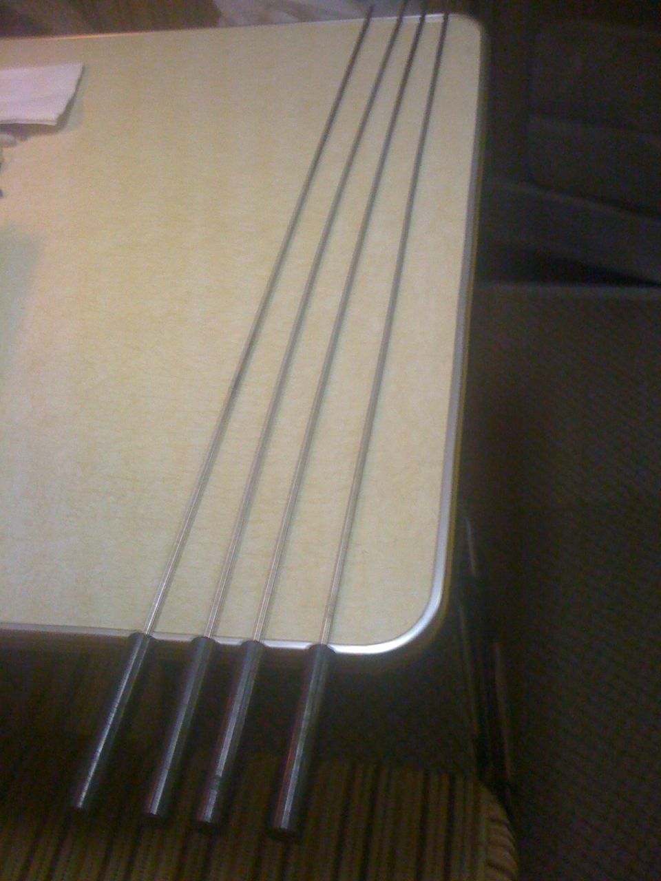Four metal rods with black handles on a light-colored table