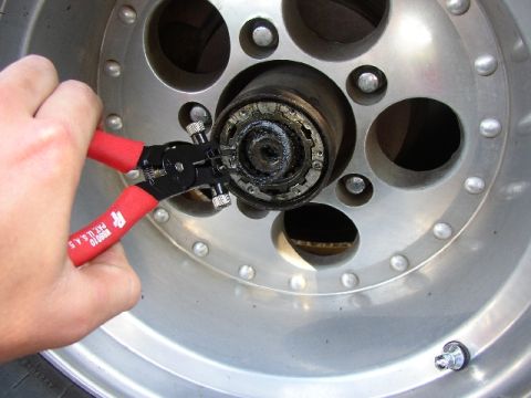 1989 Ford Bronco - Close-up of a hand manipulating a wheel hub assembly with specialized pliers.