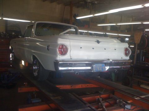 1964 Ford Ranchero - Rear view of a white pickup truck on a lift in a garage.