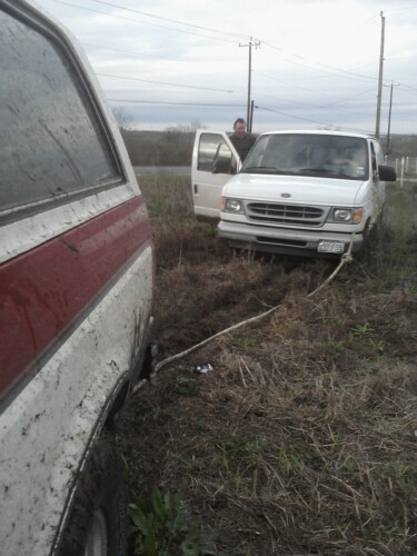 1989 Ford Bronco - Two vehicles are stuck in the mud, with a rope connecting them.
