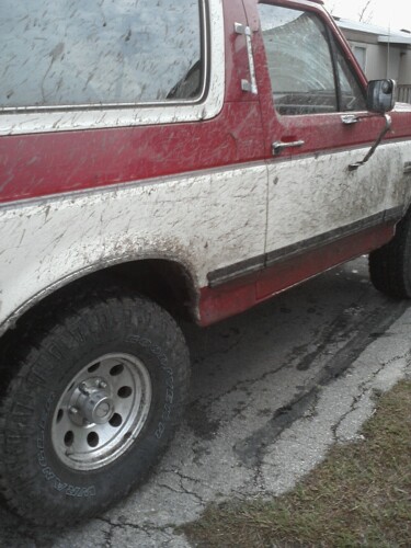1989 Ford Bronco - This two-tone SUV is covered in mud, suggesting recent off-road use.