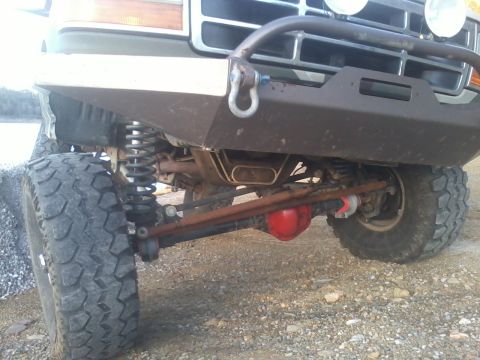 1995 Ford Bronco - The front suspension and undercarriage of a modified 1992 Ford Bronco are visible, with large off-road tires and a custom bumper.