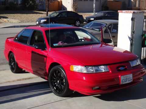 1993 Ford Taurus - This red 1993 Ford Taurus features a sunroof and aftermarket black rims.