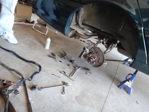 1993 Ford Taurus - Car brake repair in progress, with parts and tools laid out on the garage floor.