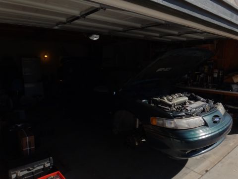 1993 Ford Taurus - A 1993 Ford Taurus SHO sits in a garage with its hood open, revealing the engine bay.