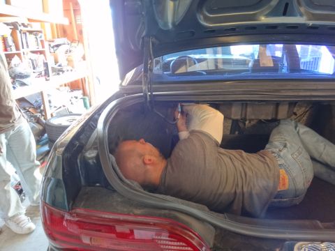 1993 Ford Taurus - A person is working inside the trunk of a car, with the trunk lid open.