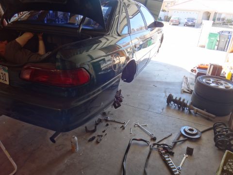 1993 Ford Taurus - A dark green 1993 Ford Taurus sedan is being worked on in a garage, with its trunk and hood open.