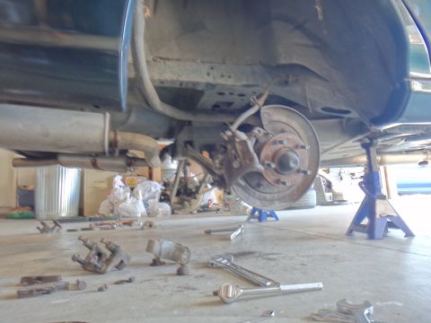 1993 Ford Taurus - Brake job in progress: rear brake assembly removed and tools laid out on the concrete floor.
