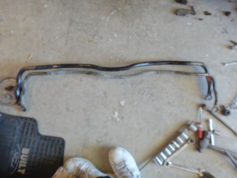 1993 Ford Taurus - Two sway bars and a Ford branded floor mat are shown on a concrete surface, along with various tools.