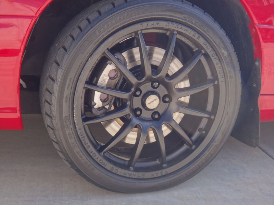 Close-up of a black Team Dynamics Motorsport wheel with a Good Year tire on a red car