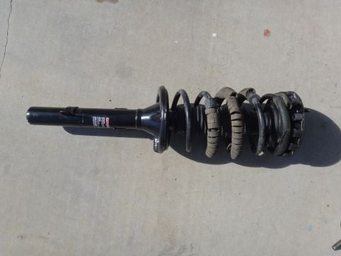 1993 Ford Taurus - A single car strut assembly with a coiled spring is shown resting on a concrete surface.