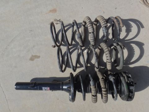 1993 Ford Taurus - Car suspension parts, including a strut and multiple coil springs, lie on a concrete surface.